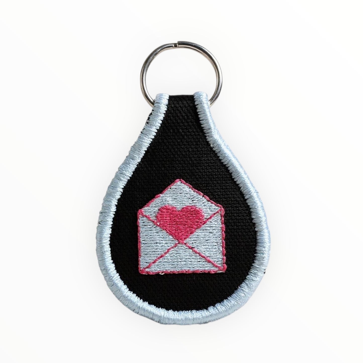 Keychain with heart-shaped envelope design on a black background